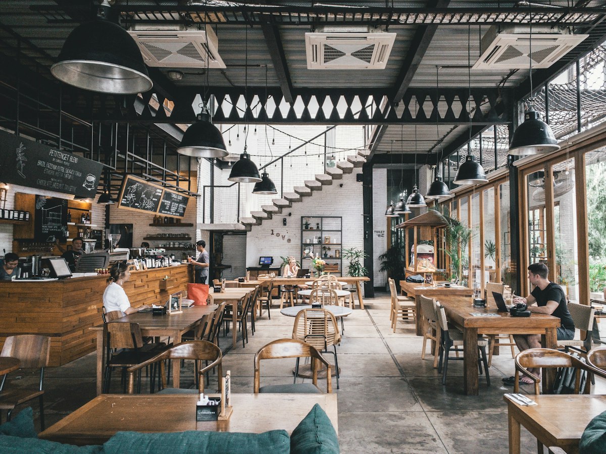 Salle du restaurant, tables en bois et grandes verrières